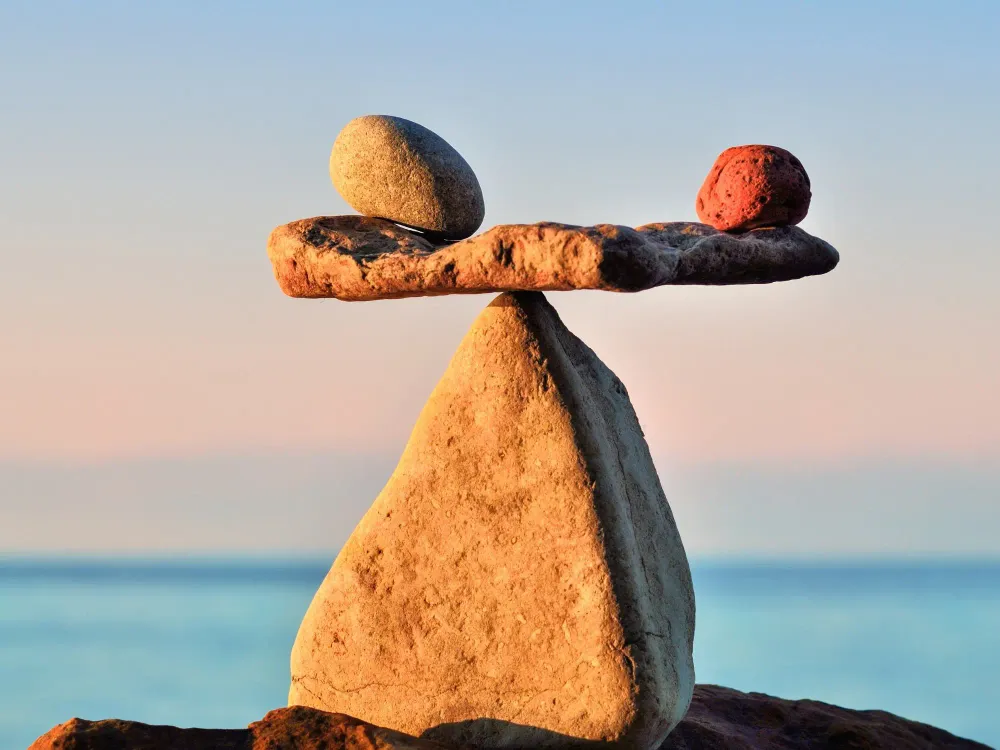 Three balanced stones at sunset with the ocean in the background.