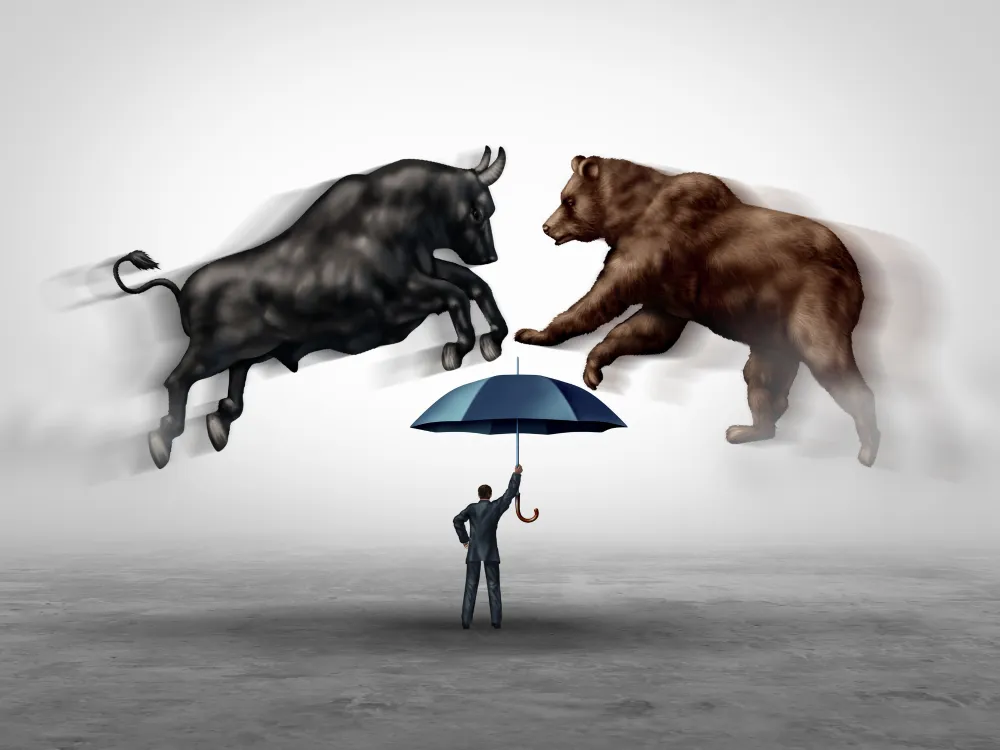 A person with an umbrella stands between a charging bull and bear, symbolizing market volatility.