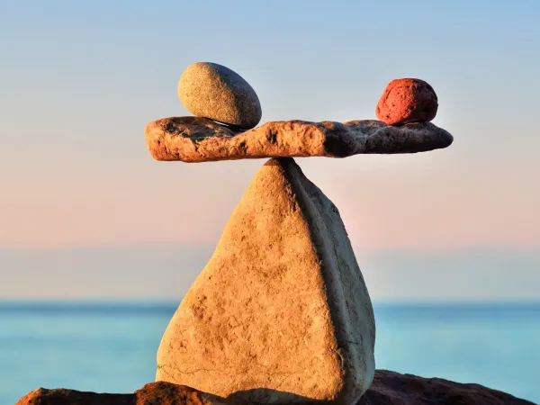 Three balanced stones at sunset with the ocean in the background.